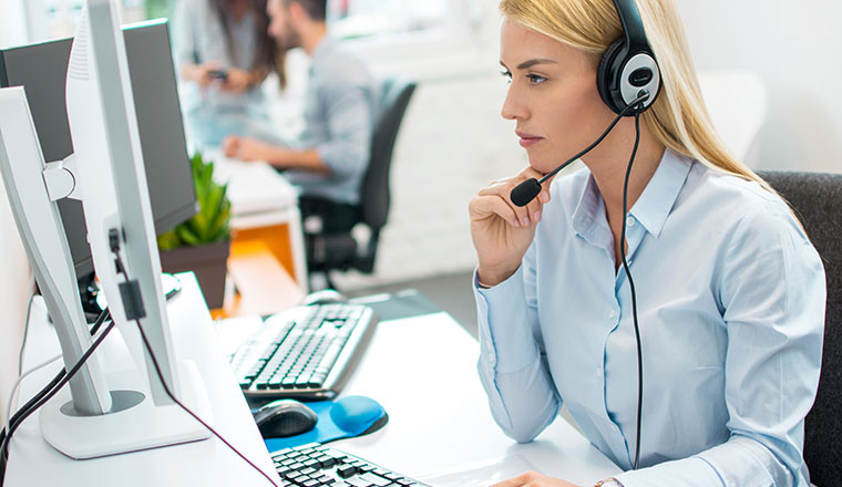 beautiful young blonde telephone operator woman working on compu